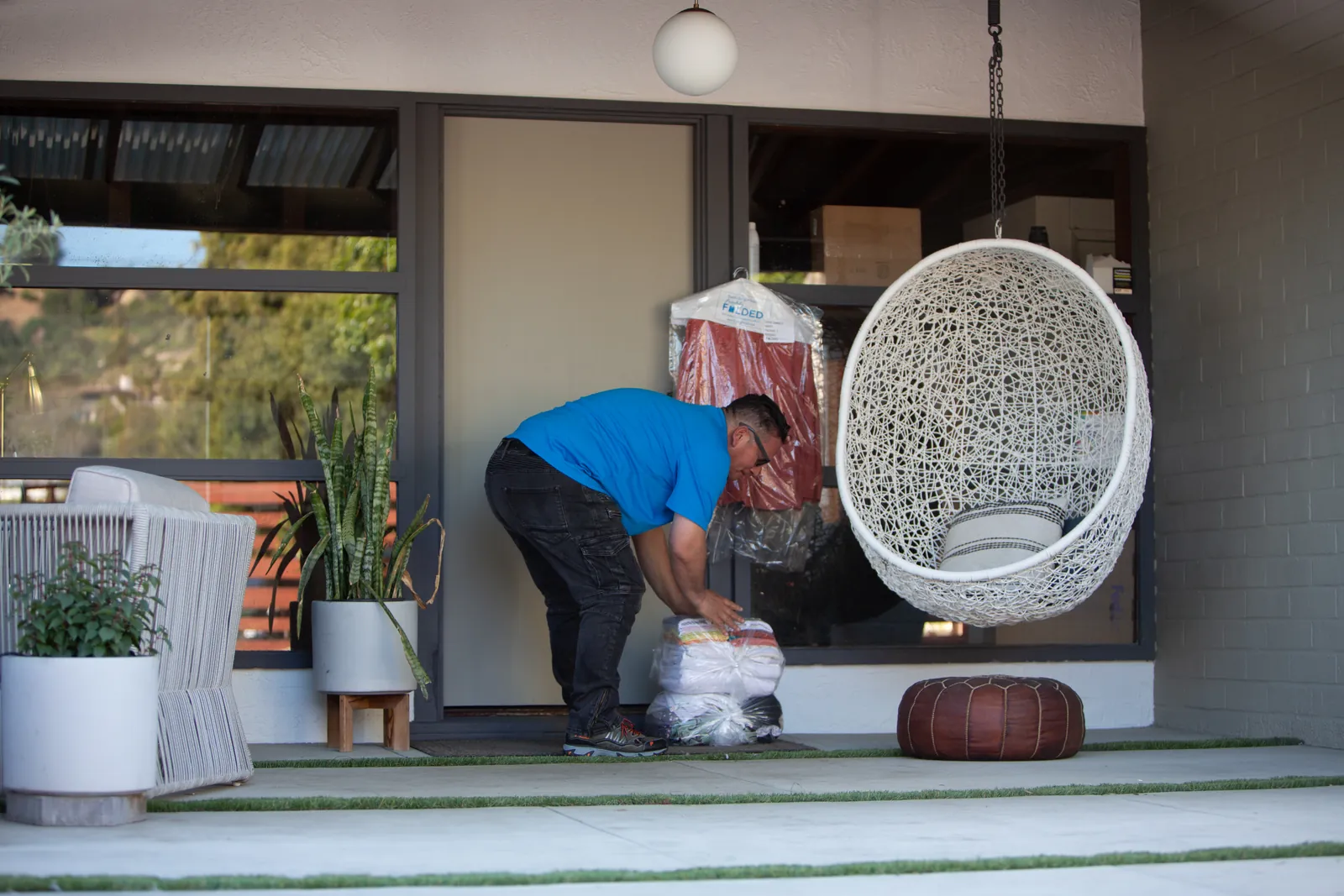 A Freshly Folded team member sets a wrapped bundle of clean laundry down at the front door of a modern home