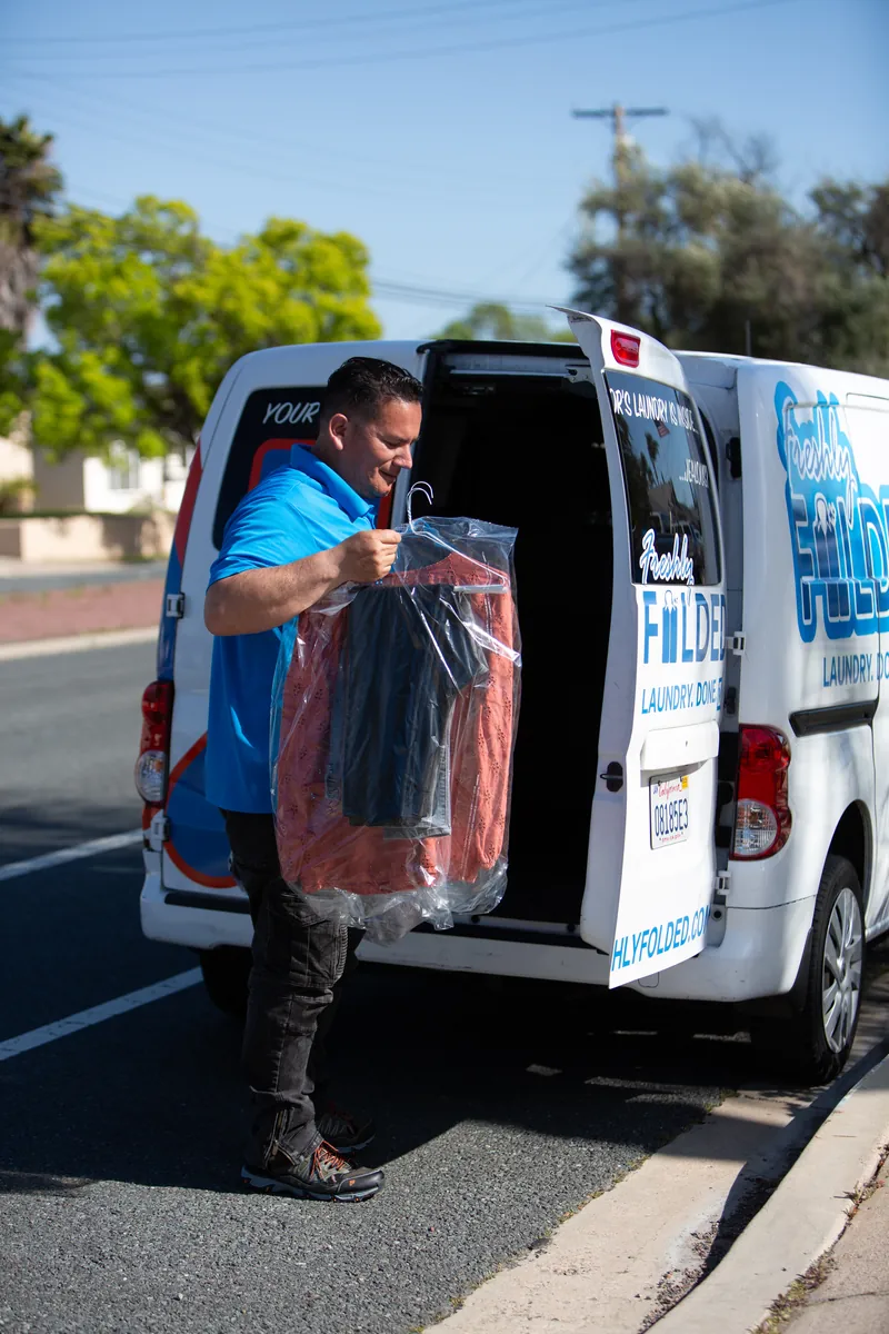 Freshly Folded driver handling garments beside the branded delivery van