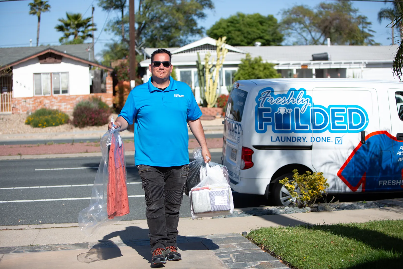 Freshly Folded driver delivering folded laundry and hanging garments beside the company van